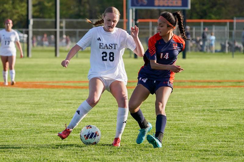 Oswego East's Olivia Hamilton (28) plays the ball against Oswego’s Alexandra Ibarra (14) during a soccer match at Oswego High School on Tuesday, April 29, 2025.