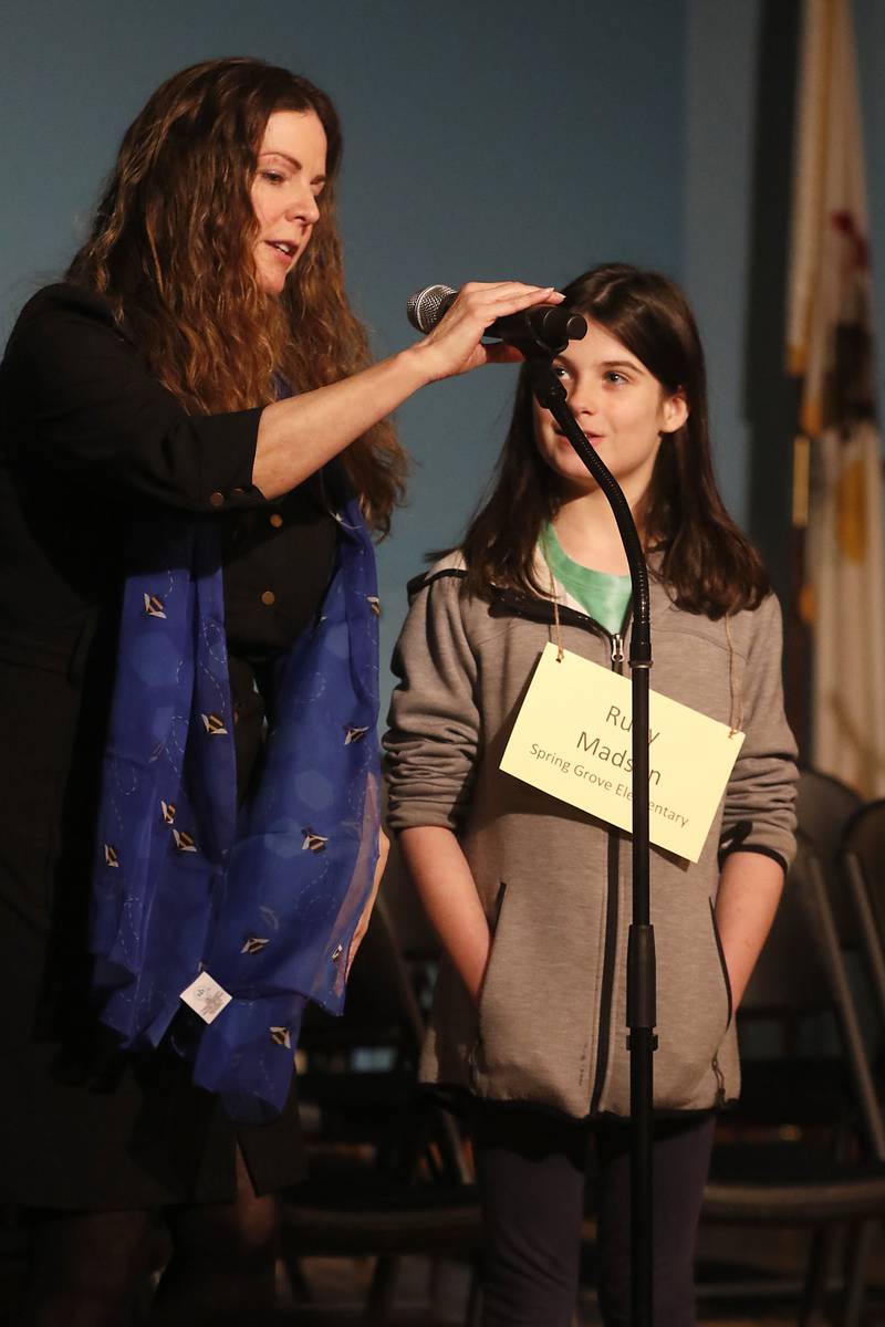 McHenry County Regional Superintendent Diana Hartmann shows Ruby Madsen of Spring Grove Elementary how to adjust the microphone before the start of the McHenry County Regional Office of Education 2023 Spelling Bee Wednesday, March 22, 2023, at McHenry County College's Luecht Auditorium in Crystal Lake.