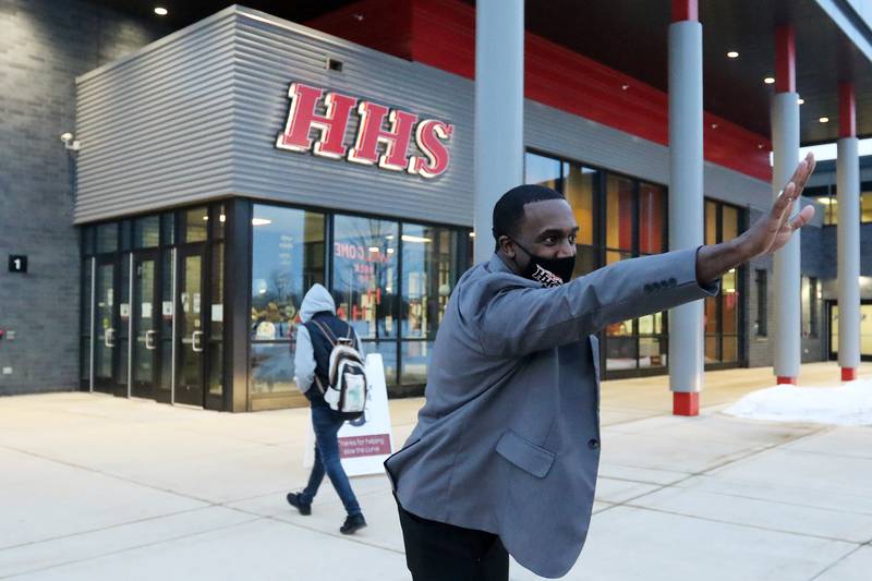 Huntley High School principal Dr. Marcus Belin waves to students and their families as students are dropped off at 7am during the first day back to hybrid learning in CUSD-158, incorporating a split between remote and in-person learning, on Monday, Jan. 25, 2021 in Huntley.