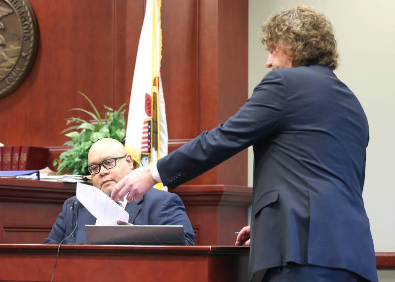 Scott Schwertley, (right) lead prosecutor in the James Corralejo case, questions David Torres, customer service and field operations manager for CAM Services, the company that provides the ankle monitor for Corralejo. Prosecutors alleged Corralejo, on release pending charges that he drove drunk and caused a Nov. 5, 2023, crash that killed DeKalb woman Graciela Reza Contreras, 59, tampered with his ankle monitor after it detected alcohol six times in March and April.