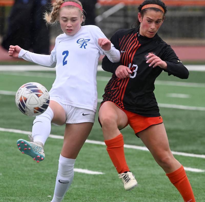 Burlington Central’s Ellie Elders, left, passes as St. Charles East’s Georggia Desario applies defensive pressure during a girls soccer match played on  Tuesday, March 26, 2024 in St. Charles.