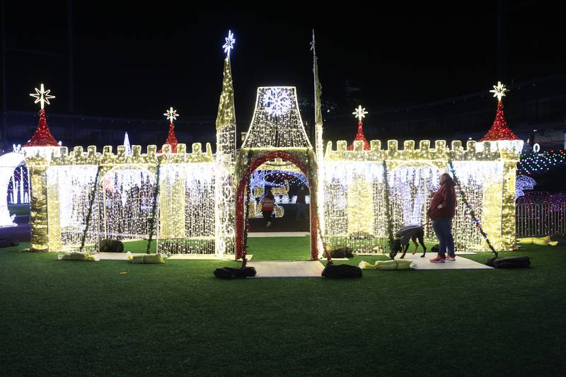 A man walks with his service dog through the lighted castle at the GLOW Holiday Festival at Slammers Stadium on Wednesday, Nov. 27, 2024 in Joliet.