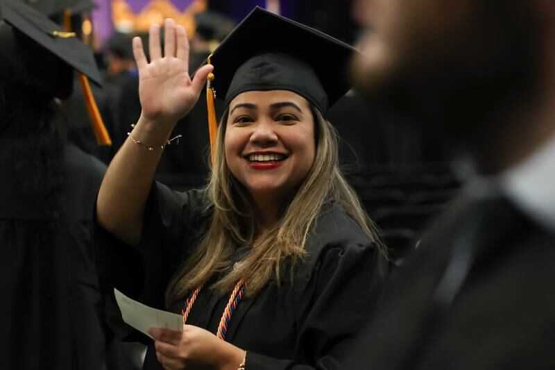 A graduate waves to family as she enters the Joliet Junior College Commencement Ceremony on Friday, May 19, 2023, in Joliet.