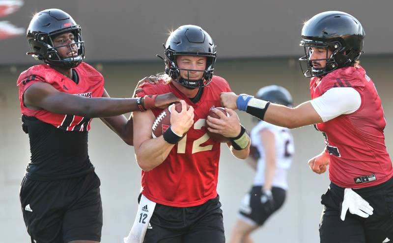 Northern Illinois Huskies quarterback Rocky Lombardi (middle) works with quarterbacks Mason Kidd (left) and Ethan Hampton during a ball security drill at the teams first practice of the season Wednesday, Aug. 2, 2023, at Huskie Stadium in DeKalb.