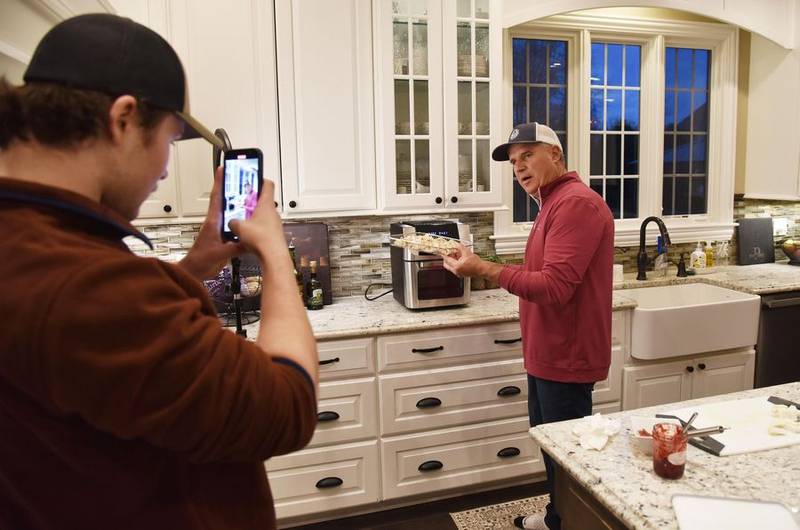 Intern Jake Konieczka, a student at North Central College in Naperville, records Darryl Postelnick as he makes a "Cooking with Darryl" TikTok video in Postelnick's Algonquin kitchen.