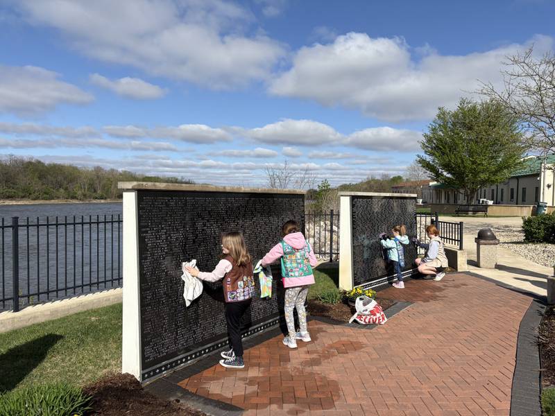 Local Girl Scouts work together to clean the walls Saturday, April 25, at the Middle East Conflicts Wall Memorial in Marseilles.