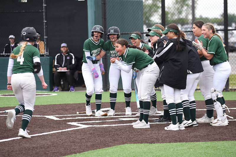 Members of the Bishop McNamara softball team greet Teagan McCue, left, at home plate after her home run during the Class 2A Coal City Regional semifinals against Manteno Wednesday, May 21, 2025.