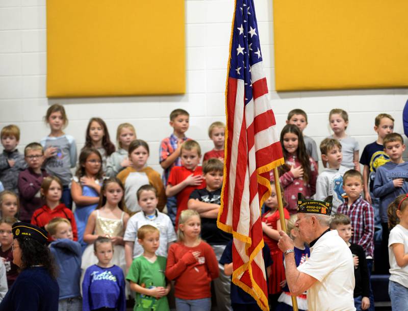 Veteran John Foxley carries the American flag past Centennial Elementary School students at the start of the school's Veterans Day ceremony on Monday, Nov. 11, 2024 in Polo.