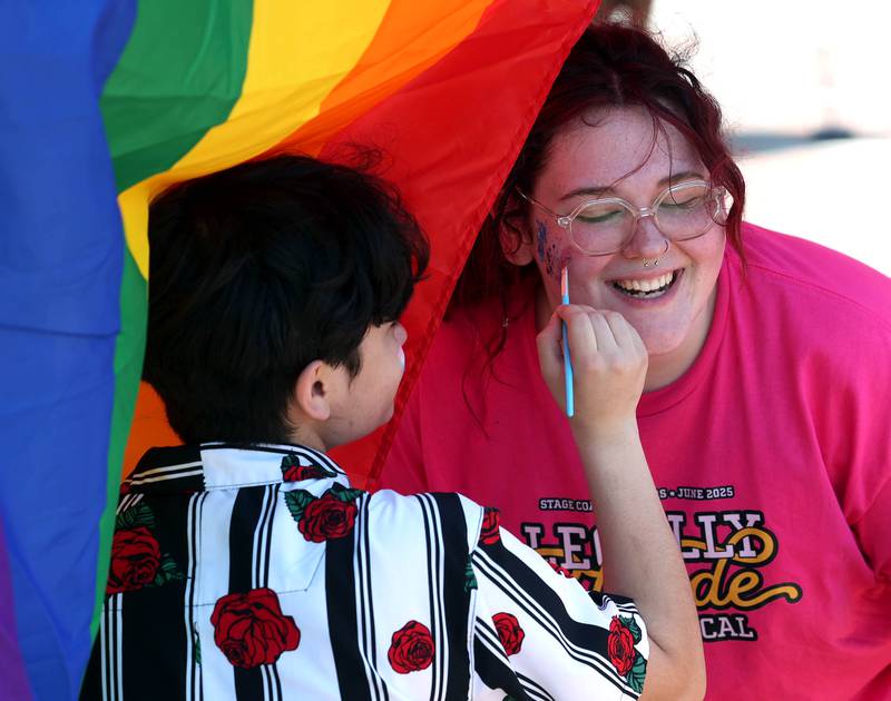 Kaleb Challgren, from DeKalb, (left) paints the face of Riley Powers, from Sycamore, at the Stage Coach Players booth Saturday, June 21, 2025, during the DeKalb Pride Fest in front of the Egyptian Theatre in DeKalb.