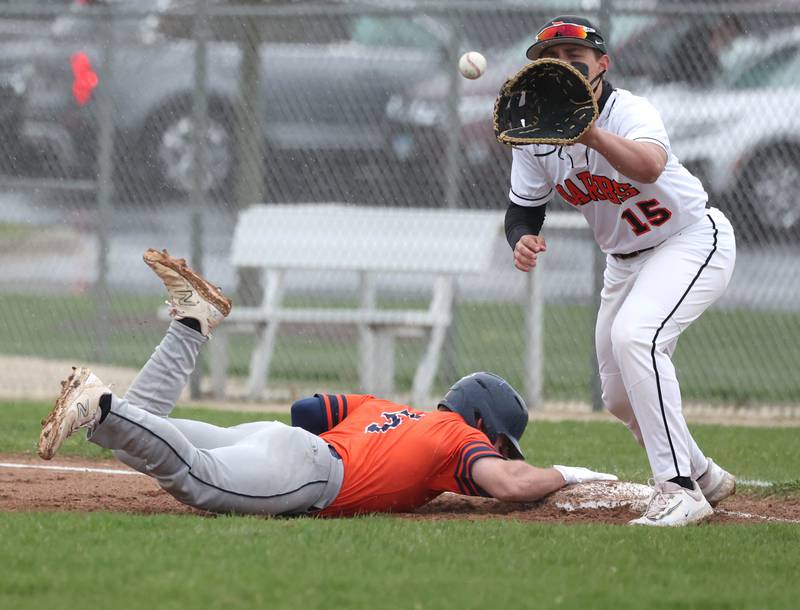 Naperville North’s Zach Bava slides safely back into first on a pickoff attempt as DeKalb's Paul Kakoliris takes the throw during their game Thursday, April 18, 2024, at DeKalb High School.