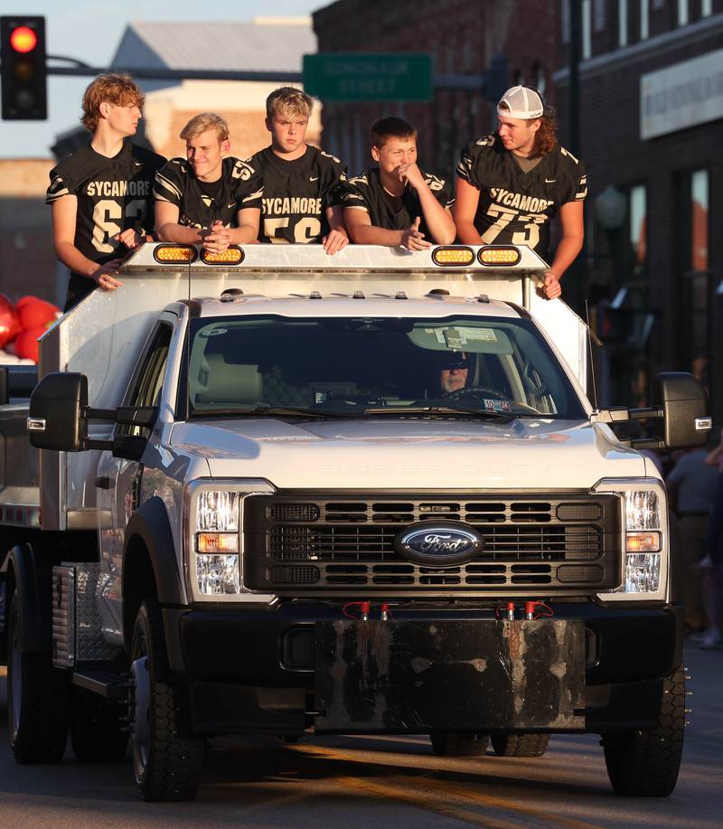 Members of the Sycamore football team ride  down State Street Wednesday, Sept. 25, 2024, during the Sycamore High School homecoming parade.