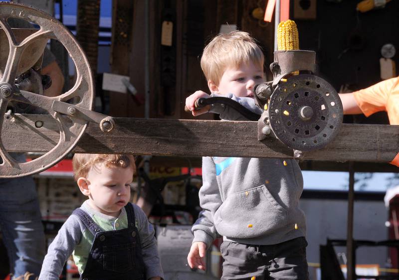 While his brother, 1-year-old Kellen watches, 3-year-old Liam Rogers of Hinckley de-kernals an ear of corn during the Sandwich Fair on Saturday, Sept. 9, 2023.