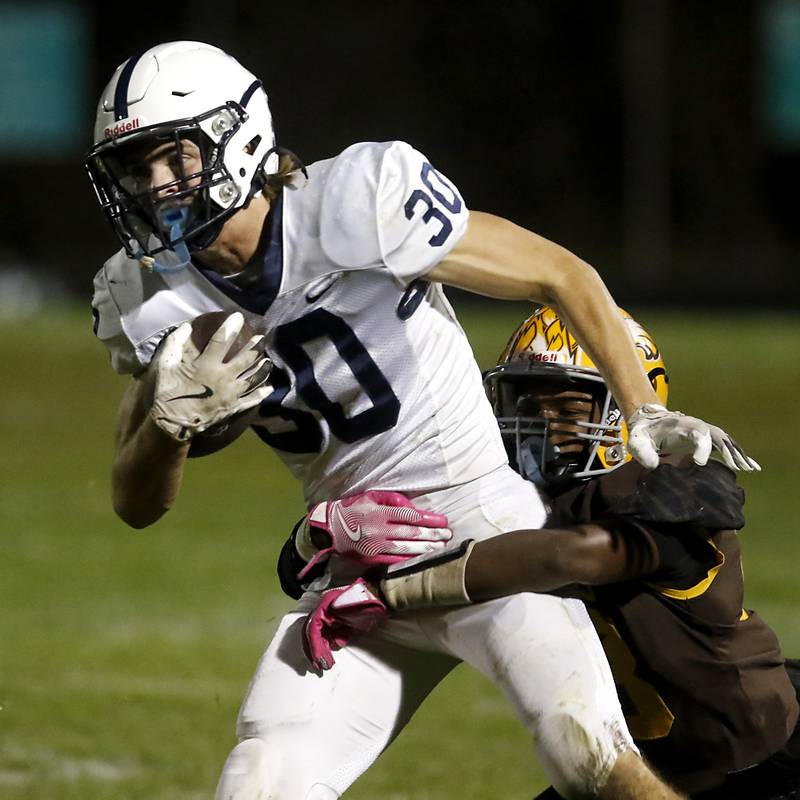 Cary-Grove's Landon Moore is tackled by Jacobs' Charlie Glenn during a Fox Valley Conference football game on Friday, Oct. 24, 2025, at Jacobs High School in Algonquin.