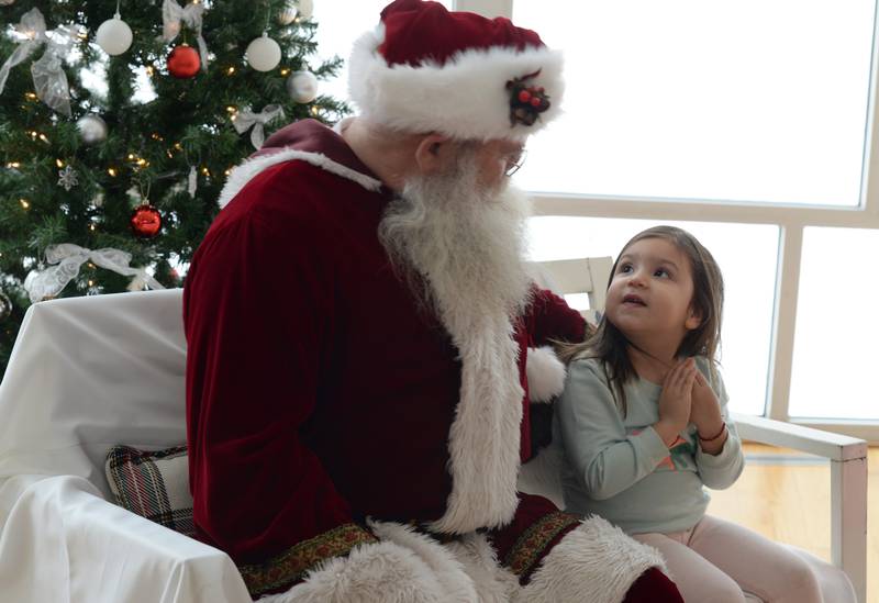 Ariela Maldonado of Milwaukee gives Santa her wish list during the Family Holiday Party at the Elmhurst Art Museum Saturday Dec 17, 2022.
