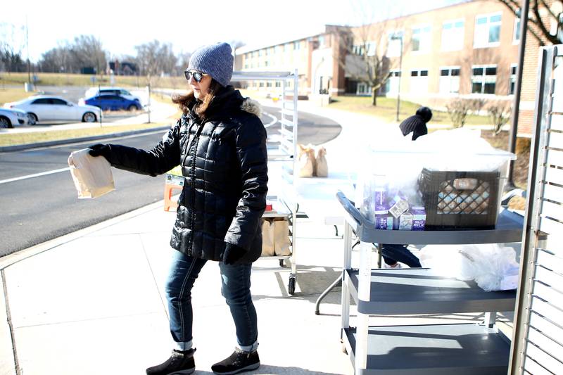 St. Charles School District 303 staff member LeeAnn Molitor hands out bags containing breakfast and lunch for district children in grades kindergarten through eighth grade. The meals are available outside Thompson Middle School every weekday from 9-11 a.m. Meals are also available to high school students at Thompson.