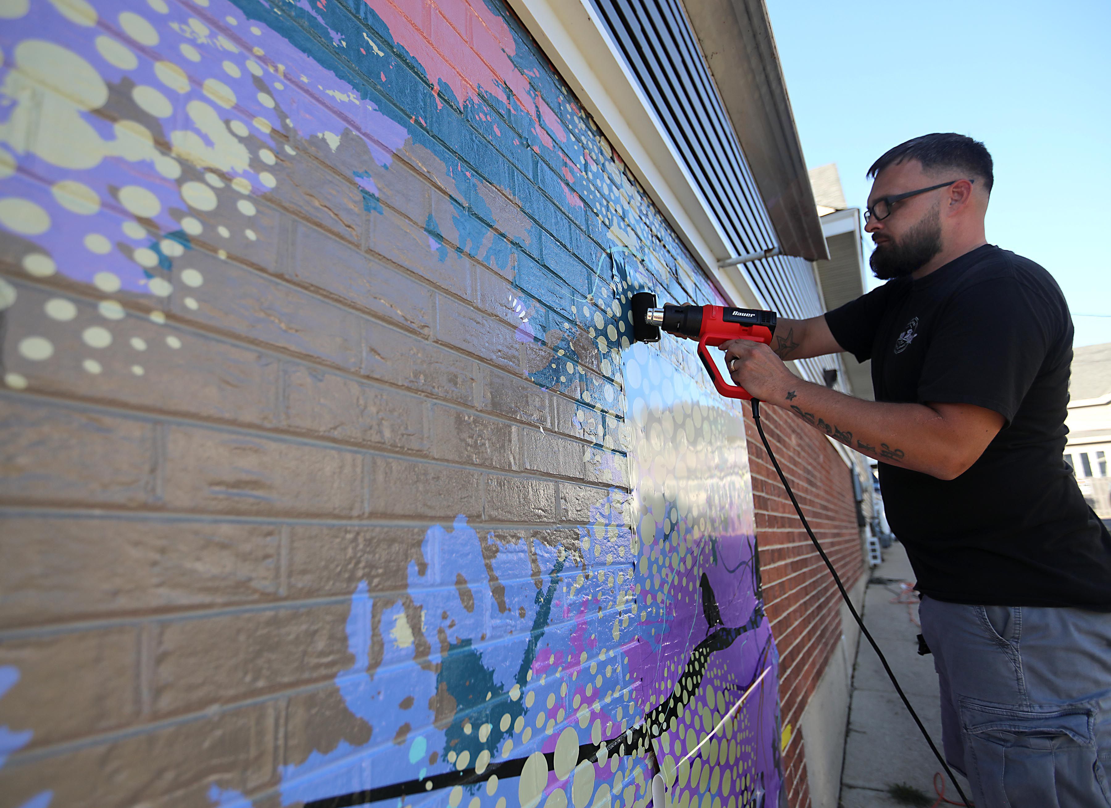 Mike Suchowski, of Invictus Vinyl, instals a new mural on Monday, Sept 15, 2025, on the side of a building at 3430 West Elm Street in McHenry. 