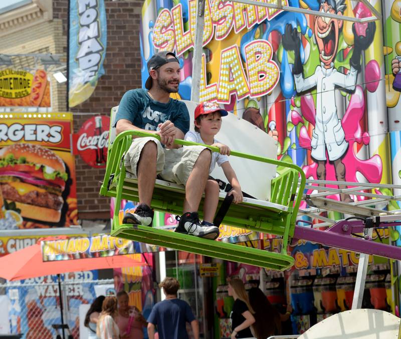 Travis Kane and his son, Tobias, of Byron, ride the Paraglider at the ByronFest carnival on Saturday, July 13, 2024 in Byron.