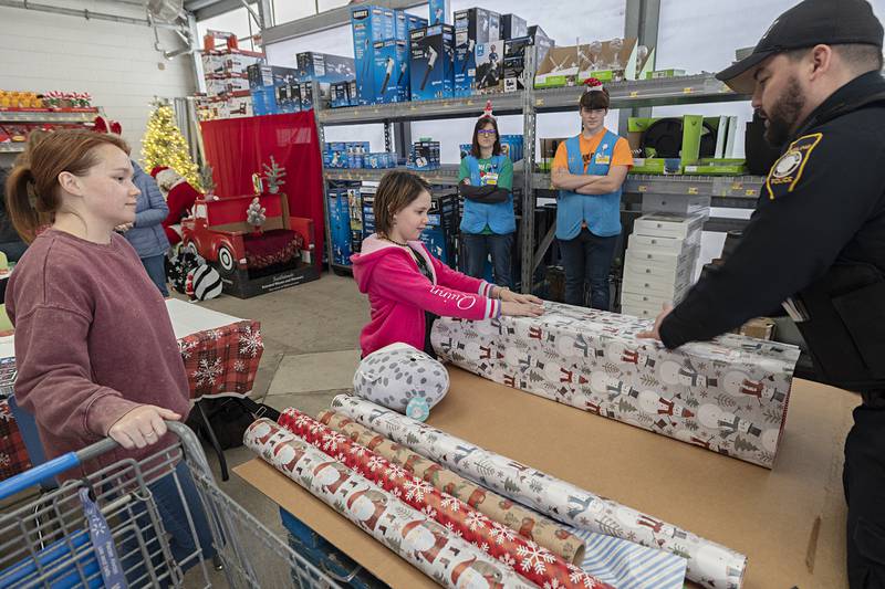 Quinn Smith, 10, and Sterling officer Tanner Wilhelm work together to wrap a gift Saturday, Dec. 10, 2022 at the Sterling Walmart.