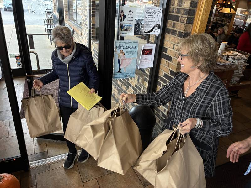 Volunteer Kathy Brown gets help getting out the door from Dorinda Koeneman, hostess at Around the Clock Restaurant in Crystal Lake. Brown was one of 21 volunteers in McHenry County who delivered Thanksgiving meals to seniors on Thursday, Nov. 27, 2025.
