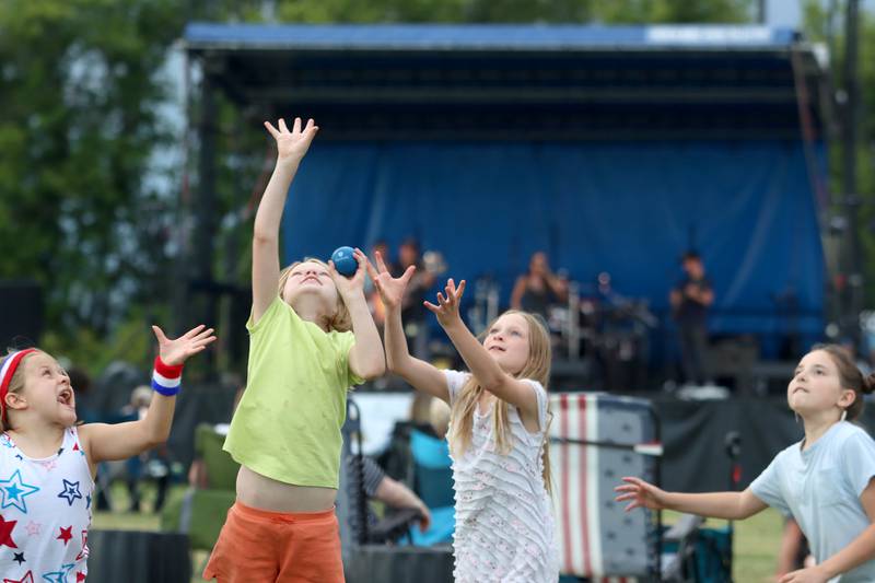 From left, Zoey Easterline, 7, Emma Sieck, 8, Penelope Sieck, 9, and Jaedin Spitson, 10, play with a ball Saturday, July 2, 2022, during the Red, White and Blue Food Truck FEASTival at Milky Way Park in Harvard.