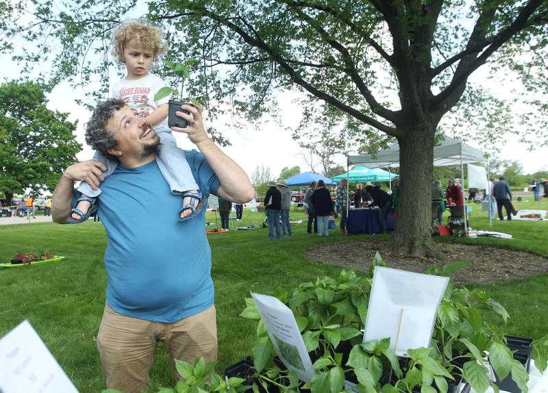 Bryan Donaldson, of Highland Park shows his son, Elliot Kramer, 2, a vegetable plant Saturday, May 20, 2023, during the Lake County Extension Master Gardener Spring Plant Sale at the University of Illinois Extension in Grayslake.