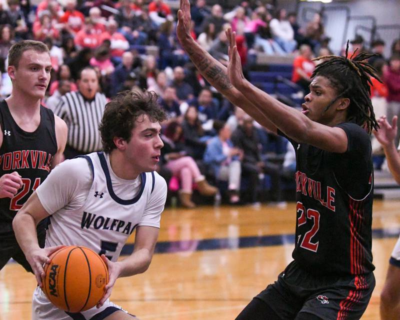 Oswego East's Josh Lopez, left, passes the ball to a teammate during the game on Friday Feb. 14, 2025, while being defended by Yorkville's Braydon Porter (22) held at Oswego East High School.