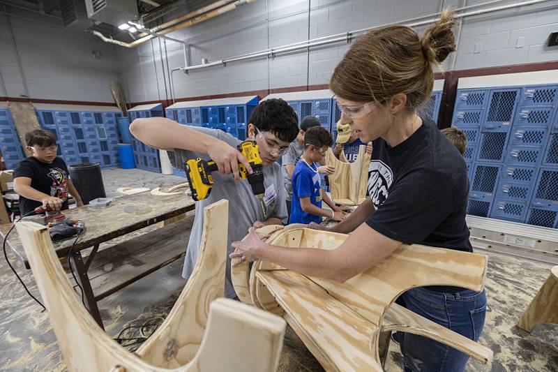 Asher Bollman, 12, is helped by WACC instructor Julia Atilano Thursday, July 13, 2023 build a stool during the woodworking portion of a summer trades camp.