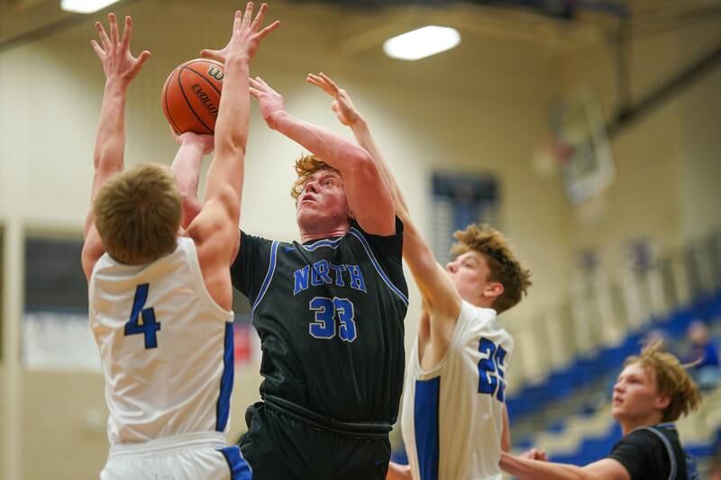 St. Charles North's Jake Furtney (33) shoots the ball in the paint against Geneva’s Brady Kafka (4) and Hudson Kirby (25) during a basketball game at Geneva High School on Wednesday, Feb 14, 2024.