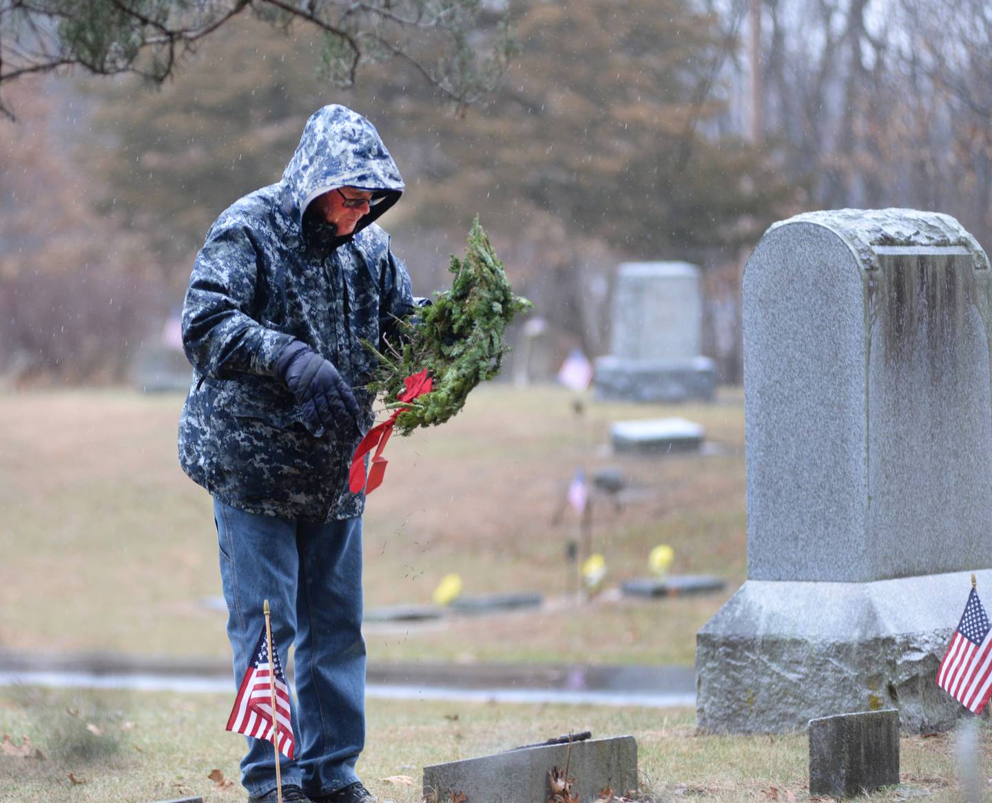 Jim Devine of Dixon prepares to lay a wreath at a veteran's grave during the Wreaths Across America event at Daysville Cemetery on Saturday Dec. 14, 2024.