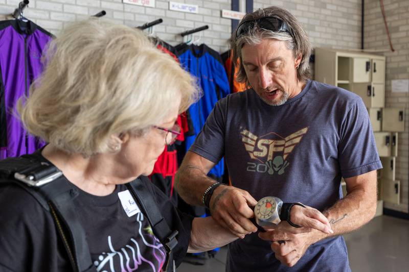 (left to right) Chad Staerkel puts Altimeter on wrist of Kathy Traegar before her big leap for a big cause on Friday, July 11, 2025 at Skydive Chicago in Ottawa.