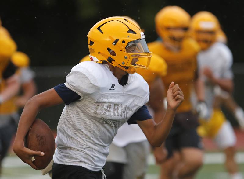 Carmel Catholic High School freshman quarterback Trae Taylor, a Crystal Lake resident, runs with the ball during practice Monday Aug. 14, 2023, at the school in Mundelein.