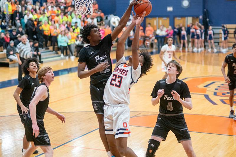 Oswego East's Jehvion Starwood (22) blocks a shot by Oswego’s Dasean Patton (23) during a basketball game at Oswego High School on Tuesday, Dec 12, 2023.