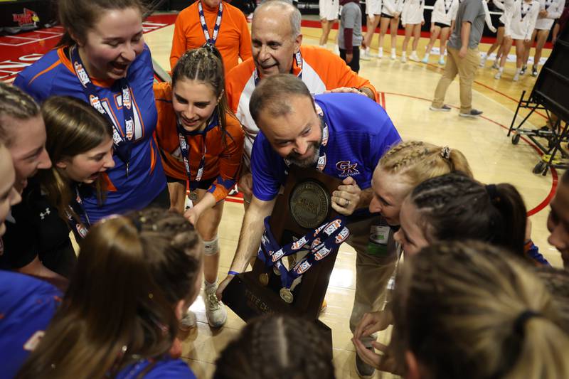 Genoa-Kingston head coach Keith Foster encourages his team while holding the championship trophy after a two set win over IC Catholic in the Class 2A championship match on Saturday in Normal.