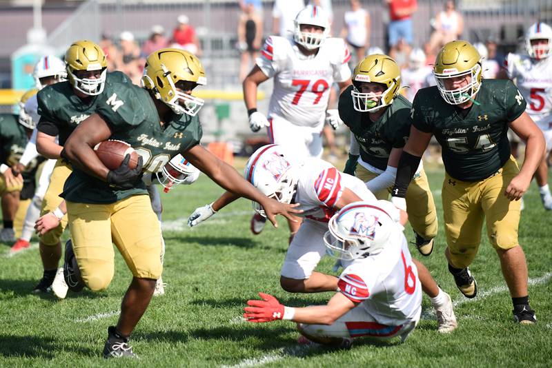 Bishop McNamara's Jordan Callaway, left, stiff arms past a pair of Marian Central defenders on his way to a touchdown during a home game Saturday, Oct. 4, 2025.