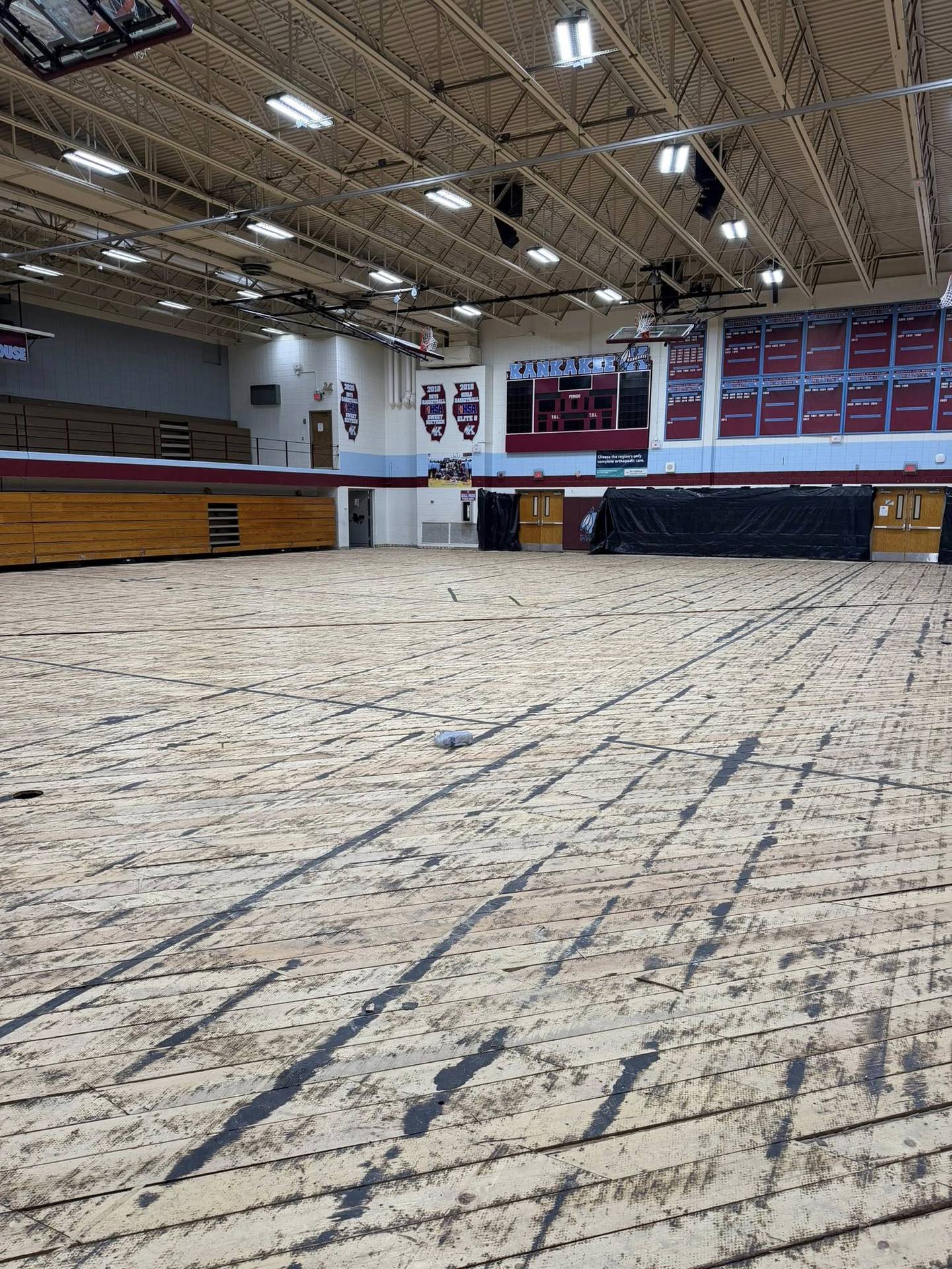 The Kankakee High School gym floor was removed following damage from the March 10 storms, showing the base layer of flooring in a post on April 1, 2026. Some areas of the subfloor have messages from the past.