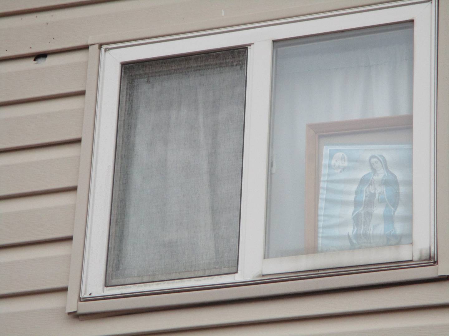 A stray bullet hit the wall but missed the window of a Henderson Avenue house with a picture on display of Our Lady of Guadaulpe. Joliet. Oct. 31, 2022.