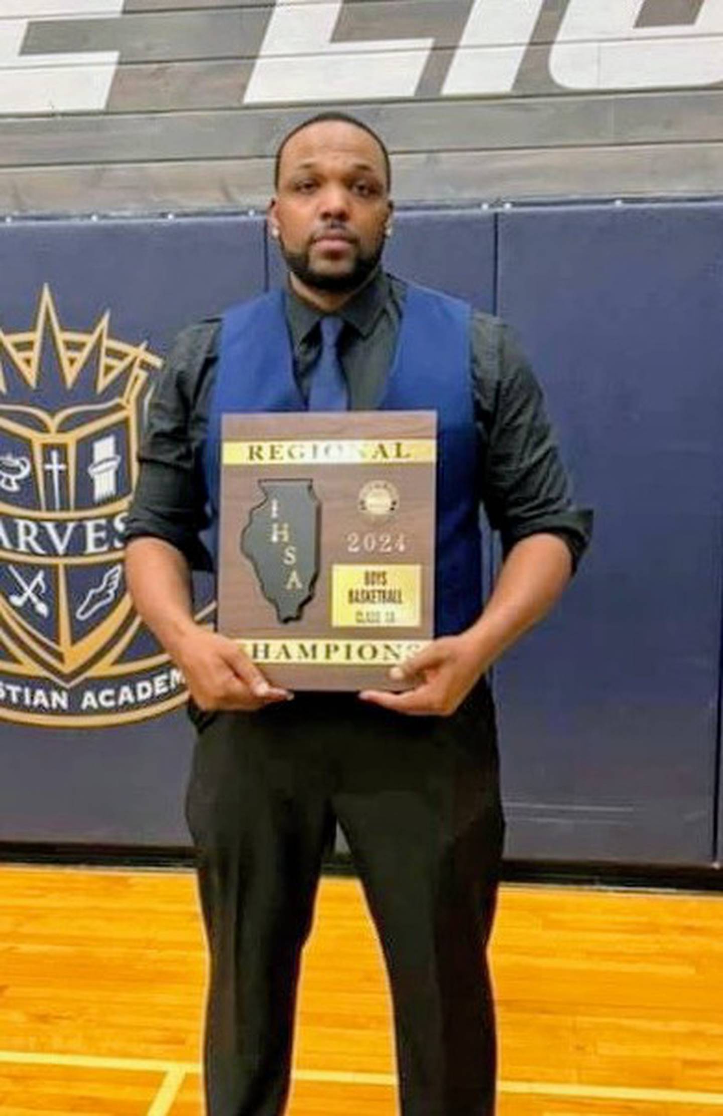 Lafeyette Ball holds the championship plaque after he coached Harvard Christian Academy's boys basketball team to a Class 1A regional title in 2024. Bell is the new boys coach at Marian Central.