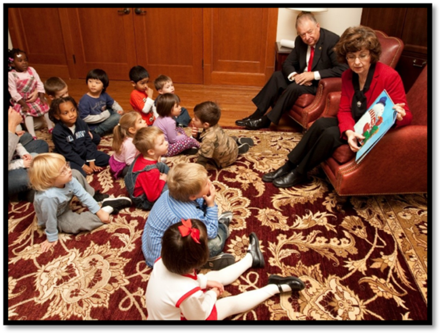 The late Barbara Cole Peters (right) sits next to her husband and NIU President John Peters (top left) as she reads a book to children during NIU's Holiday Open House in this undated photo. Peters, who died on Nov. 11, 2024, was NIU's First Lady when her husband, John Peters, was NIU president.