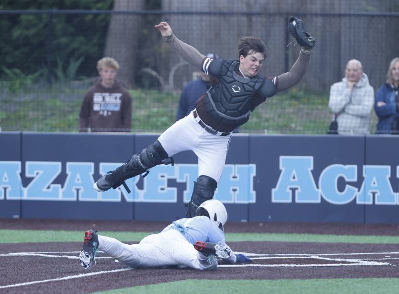 Nazareth's Jaden Fauske (21) slides into home to score the winning run as Joliet Catholic's Zachary Pomatto (34) catches the ball during the varsity baseball game on Wednesday, April 20, 2025 between Nazareth and Joliet Catholic academies in La Grange Park.