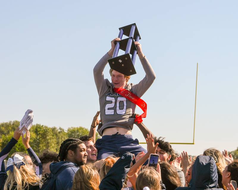 Oswego East junior and homecoming king Andrew Pohlman raises up the spirit trophy after the junior class won the spirit award on Friday Oct. 4, 2024, during the homecoming pep assembly held at Oswego East’s football stadium.