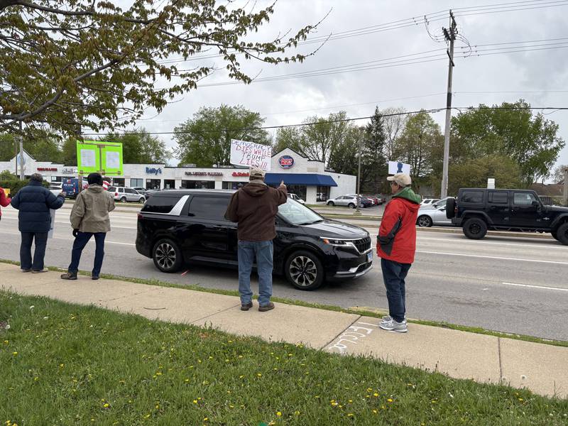 Protestors hold up signs during a May 1 protest in McHenry Friday May 1, 2026.