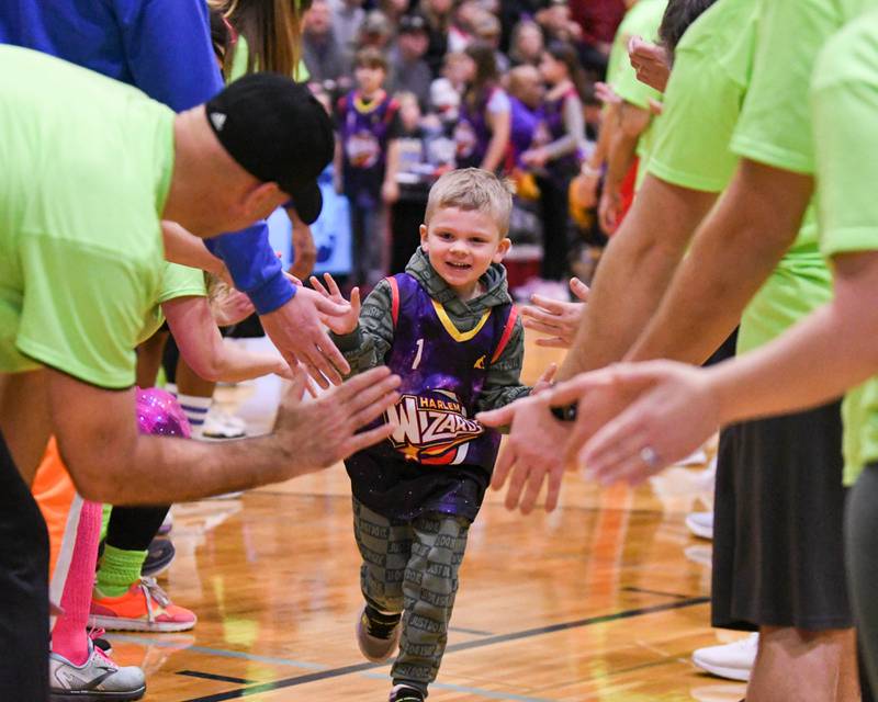 Thomas Meagher, 6, of Downers Grove runs through a tunnel of Downers Grove school district staff members after having his named announce on Sunday Jan. 19, 2025, before the start of the Harlem Wizard game held at Downers Grove South High School.