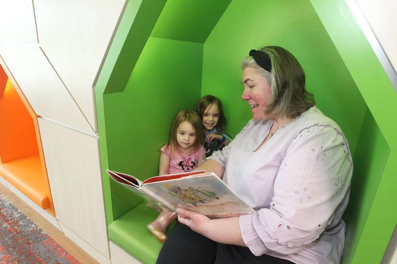 Library Director Jennifer Drinka reads a children's book to her nieces, Mia Groth, 3, of Libertyville and her sister, Emma, 5, on May 13 in The Neighborhood, during the Antioch Public Library District Open House in Antioch.