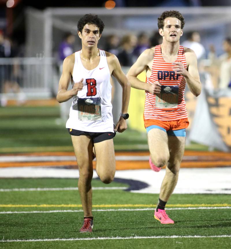 Batavia’s Francesco Benelli (left) and Oak Park-River Forest’s Liam O’Connor runs to the finish of the boys varsity race during the Naperville North Twilight Cross Country Invitational on Wednesday, Oct. 9, 2024 in Naperville.