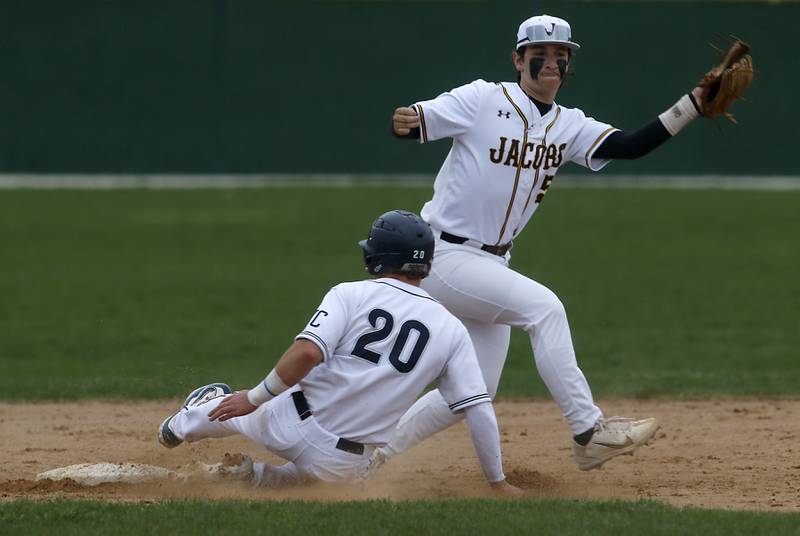 Cary-Grove's Hayden Dieschbourg slides into second base as Jacobs' Gage Martin tries to filed the ball during a Fox Valley Conference baseball game on Wednesday, April 17, 2024, at Cary-Grove High School. The game was stopped for darkness after the 9th inning with the score tied 6-6.