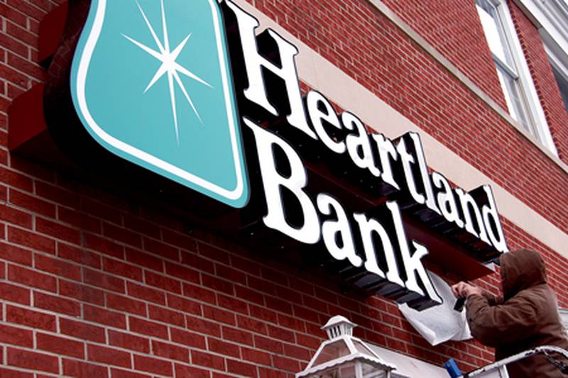 Tom Nink of Designs & Signs by Anderson of Ottawa installs the new Heartland Bank illuminated sign at the bank's main branch on South Main Street in Princeton.
