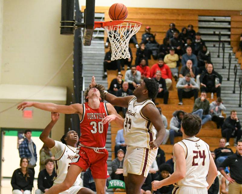 Yorkville's Bryce Salek, center makes a basket while being defended by St. Ignatius's Justin Scott, right, and fouled by St. Ignatius's Reggie Ray (25) in the second quarter on Tuesday Dec. 26, 2023, during the Jack Tosh tournament held at York High School in Elmhurst.