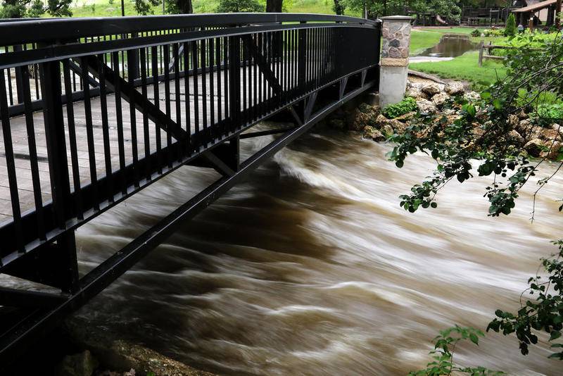 Water rushes under a walking bridge Wednesday, June 27, 2018, at Towne Park in Algonquin.