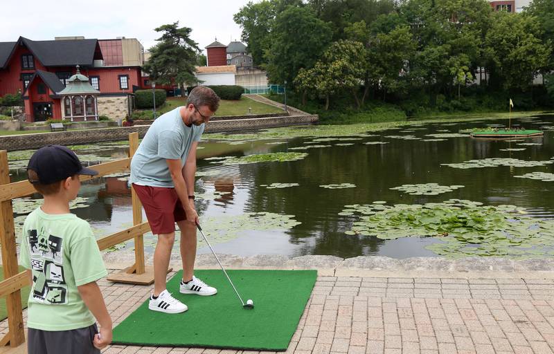 Geoffrey Booth, of Aurora, tries the golf challenge while his 8-year old son Owen watches, at the annual Batavia Windmill City Festival on Saturday, July 12, 2025.