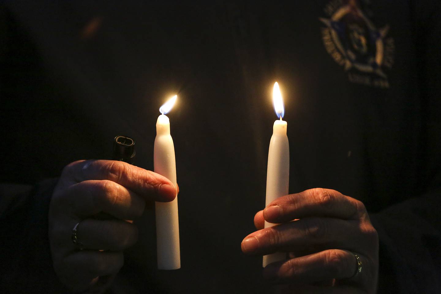 A volunteer distributes candles to vigil attendee on Tuesday, Jan. 26, 2021, at Silver Cross Hospital in New Lennox, Ill. Family, friends and coworkers attended a candlelight vigil for Deputy Ken Kostecki of the Will County Sheriffs office who is currently on a ventilator as he battles COVID-19.
